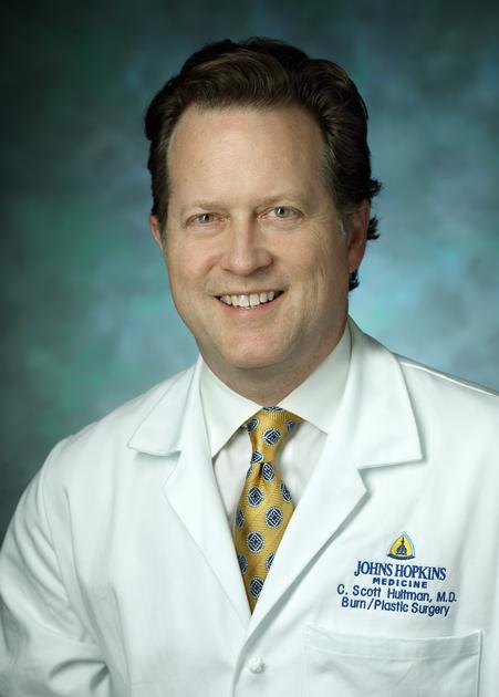 Scott Hultman shown in formal headshot portrait, wearing medical white coat.
